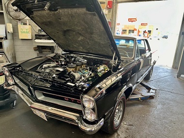 1965 Pontiac with hood up for repair inside the service bay at Batavia Avenue Mobil in Batavia, IL